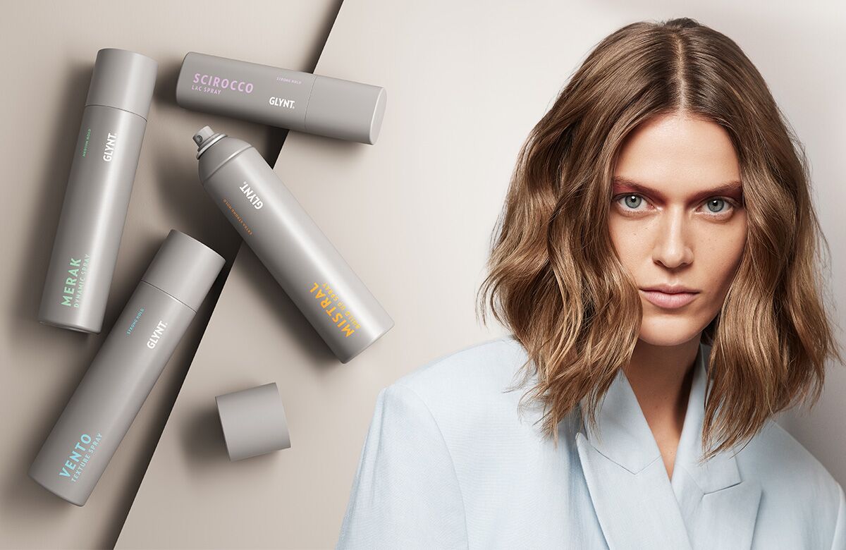 GLYNT Haarspray Produktabbildung neben einem weiblichen Model mit voluminösem Haar